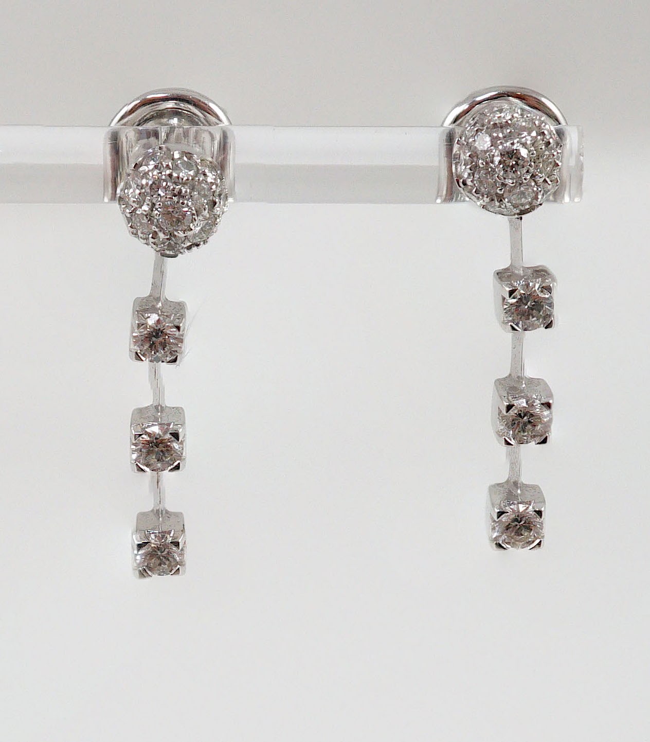 A modern pair of 18ct white gold, diamond cluster and three stone diamond drop set earrings